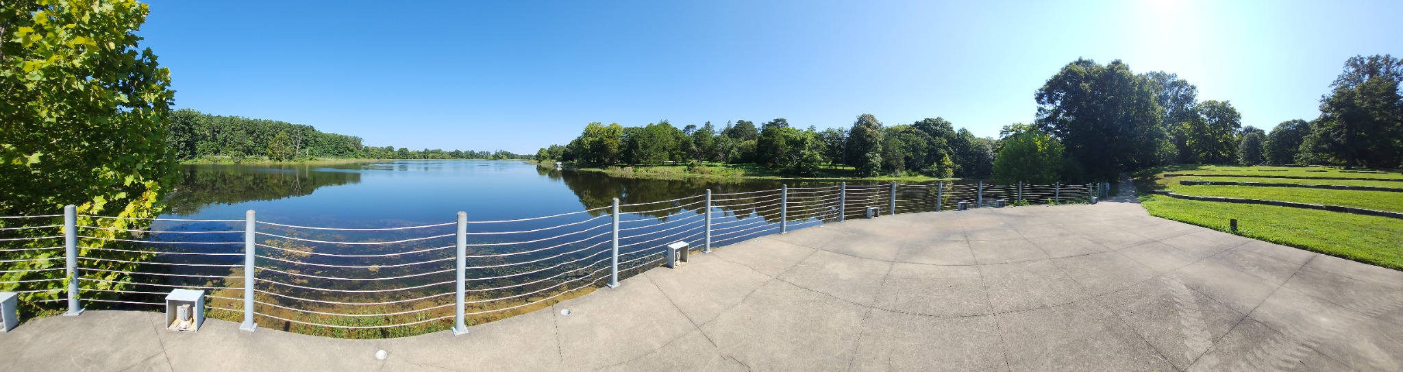 A panoramic view of the lake, trees, walkway, and open lawn at Bernheim Forest